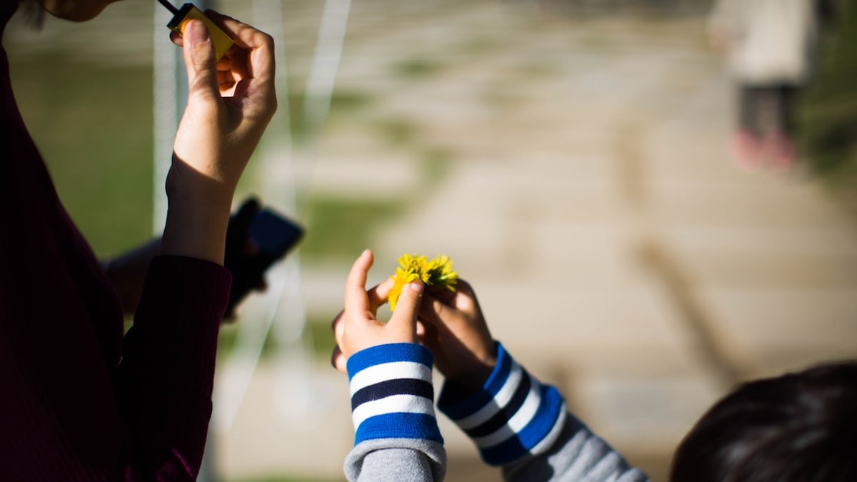 a woman holding a child's hand with a flower in it